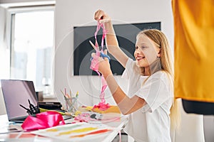 Cheerful seamstress scissoring off a strip of organza fabric