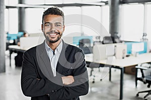 Cheerful self confident man with crossed hands portrait. Handsome young businessman with folded arms in the office