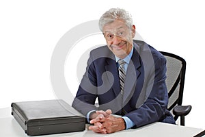 Cheerful senior business man sits at desk