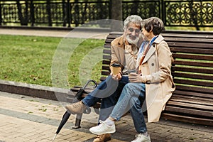 cheerful senior couple in coats holding