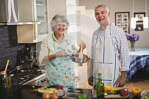 Cheerful senior couple cooking in kitchen at home