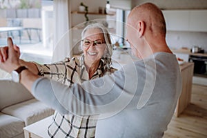 Cheerful senior couple dancing together at home.