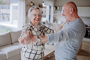 Cheerful senior couple dancing together at home.