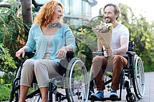 Cheerful senior couple having a wlak in the wheelchairs