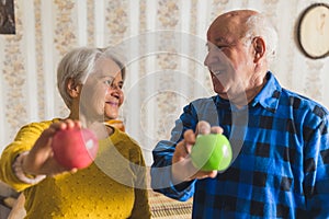 cheerful senior couple holding fresh apples in the living room medium closeup indoor healthy lifestyle concept