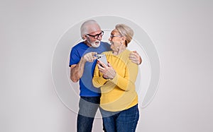 Cheerful senior couple looking at each other and reading good news over phone on white background