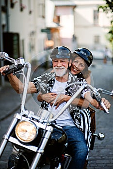 A cheerful senior couple travellers with motorbike in town. photo