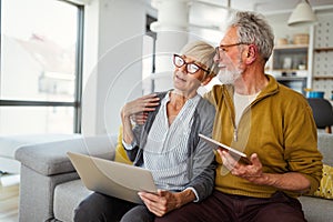 Cheerful senior couple using technology devices and having fun at home