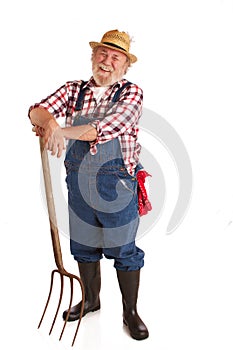 Cheerful senior farmer leaning on hay fork