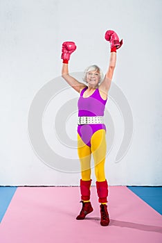 cheerful senior female boxer raising hands and smiling