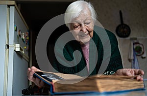 Elderly widowed woman holds photos of her deceased husband and gets emotional on valentine`s day remembering old times.