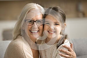 Cheerful senior grandmother and happy little granddaughter home family portrait