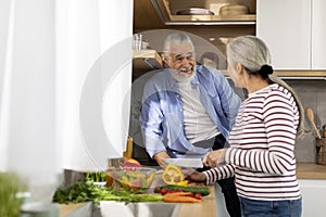 Cheerful Senior Husband And Wife Cooking Healthy Lunch In Kitchen Together