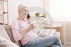 Cheerful senior lady having phone call on her smartphone