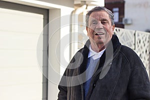 Cheerful senior man in front of house