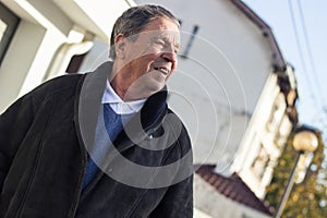 Cheerful senior man in front of house