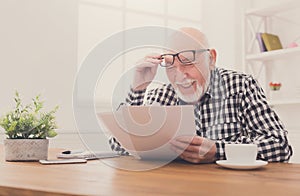 Cheerful senior man looking photos, copy space