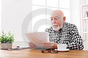 Cheerful senior man looking photos, copy space