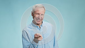 Cheerful senior man shaking his finger to camera and laughing, playfully reproaching, enjoying joke and tricks