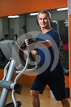 Cheerful senior man working in gym