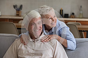 Cheerful senior married couple relaxing in home living room