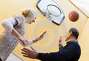 Mature couple playing basketball in patio