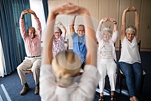 Cheerful senior men and women exercising with female doctor