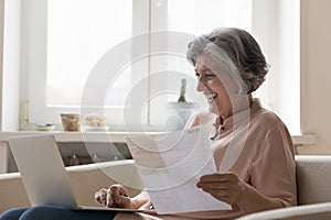 Cheerful senior retired woman paying bills on Internet