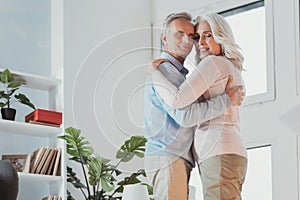 Cheerful senior spouses hugging and dancing