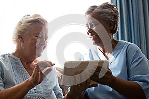 Cheerful senior woman with doctor using digital tablet while sitting on sofa