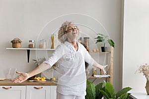 Cheerful senior woman enjoys carefree life dancing in the kitchen photo