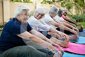 Cheerful senior woman with friends doing stretching exercise