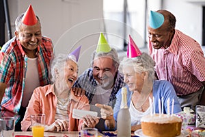 Cheerful senior woman showing mobile phone to friends in party