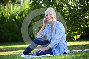 Cheerful senior woman sitting down talking on the phone