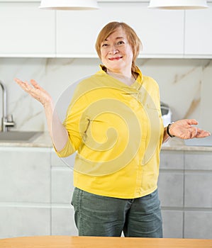 Cheerful senior woman standing in her kitchen smiling