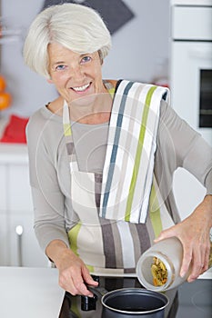 cheerful senior woman standing by stove in kitchen photo