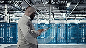 Cheerful server room engineer troubleshooting backend operations using tablet