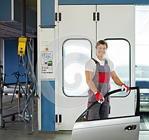 Cheerful serviceman in a car body workshop photo