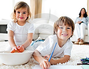 Cheerful siblings eating chips and drawing