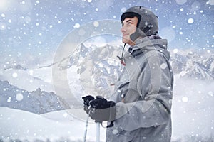 Cheerful skier looking afar before starting to skiing. Happy man enjoying holiday in winter season. Smiling mountaineer skier in w