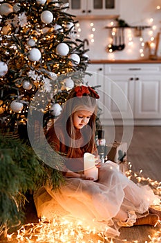 Cheerful small girl indoors at home at Christmas, holding candle