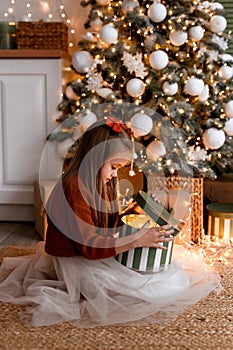 Cheerful small girl indoors at home at Christmas, holding gift