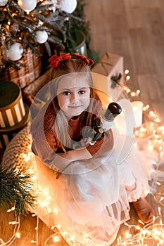 Cheerful small girl indoors at home at Christmas, holding gift