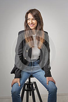 Cheerful smiling brunette haired woman sitting at isolated background