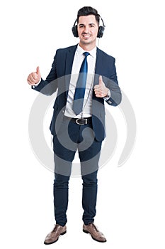 Cheerful smiling businessman listening music and thumb up