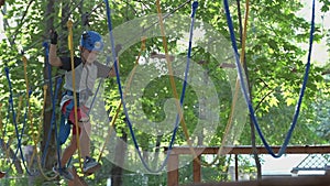 Cheerful smiling child climbing in adventure high wire park.
