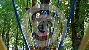 Cheerful smiling child climbing in adventure high wire park.