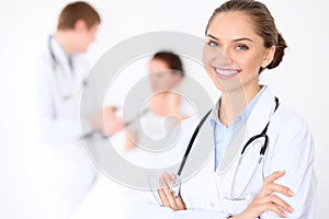 Cheerful smiling female doctor on the background with doctor and his patient in the bed. High level and quality of