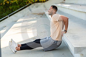 Cheerful and smiling hispanic man doing outdoor exercise in stadium, man stretching and recuperating before jogging in