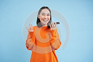 Cheerful smiling korean woman talk on speakerphone, records voice message, learns how to speak using language learning